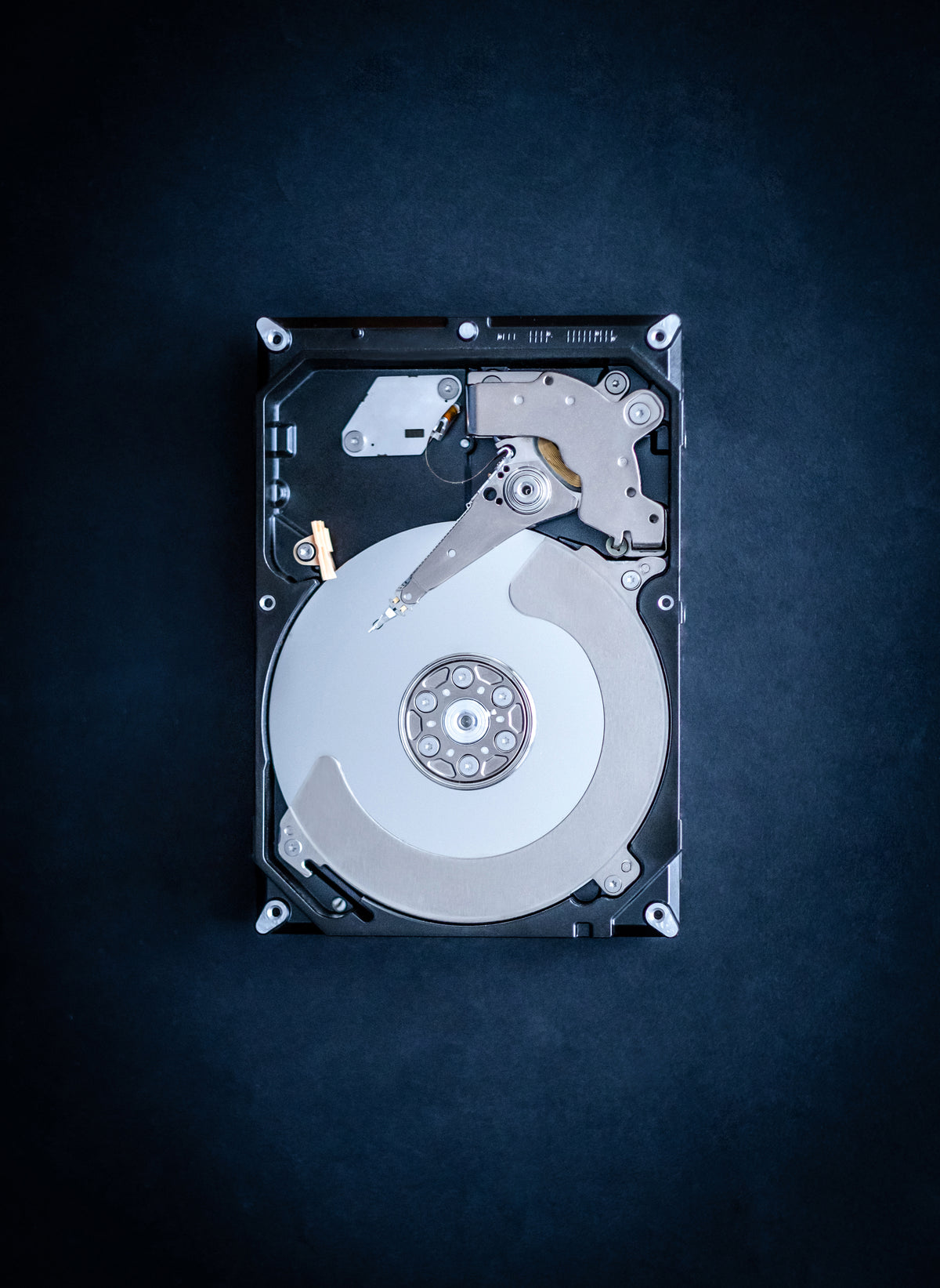 Open hard disk drive showing platter and read-write head, representing secure data destruction