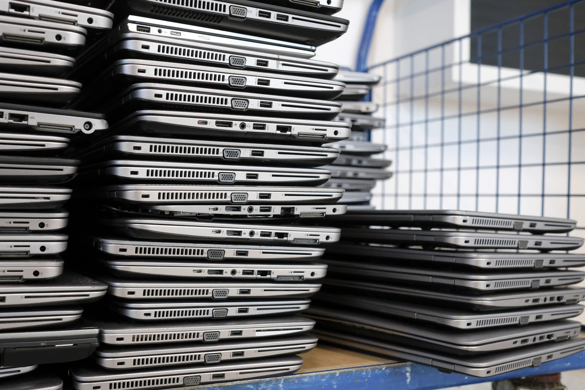 Large stacks of redundant business laptops piled on a trolley awaiting collection