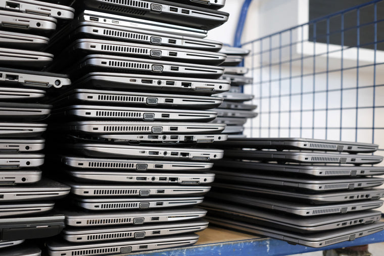 Large stacks of redundant business laptops piled on a trolley awaiting collection